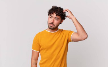 İspanyol yakışıklı adam şaşkın ve şaşkın hissediyor, başını kaşıyor ve yana bakıyor.