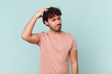 İspanyol yakışıklı adam şaşkın ve şaşkın hissediyor, başını kaşıyor ve yana bakıyor.