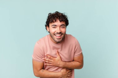 İspanyol yakışıklı adam komik bir şakaya yüksek sesle gülüyor, mutlu ve neşeli hissediyor, eğleniyor.