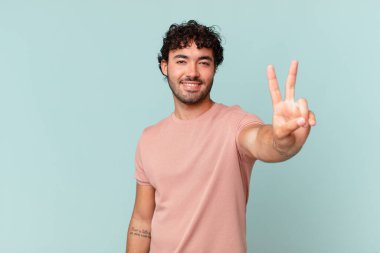 İspanyol yakışıklı adam gülümsüyor ve mutlu görünüyor, kaygısız ve olumlu, zafer ya da barışı simgeliyor.