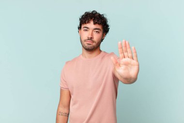 İspanyol yakışıklı adam ciddi, sert, hoşnutsuz ve kızgın görünüyor. Avuç içinin açık olması jesti durduruyor.