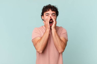 İspanyol yakışıklı adam mutlu, heyecanlı ve pozitif hissediyor. Elleri ağızda, bağırıyor.