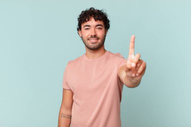 İspanyol yakışıklı adam gülümsüyor ve arkadaş canlısı görünüyor, bir numara ya da ilk eli önde, geriye doğru sayıyor.