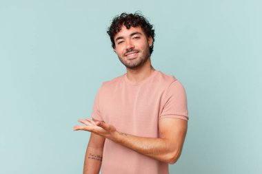 İspanyol yakışıklı adam neşeyle gülümsüyor, kendini mutlu hissediyor ve fotokopi uzayda avucunun içinde bir konsept gösteriyor.