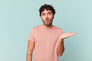 İspanyol yakışıklı adam şaşırmış ve şoka uğramış görünüyor, çenesi düşmüş, bir objeyi elinde açık bir elle tutuyor.