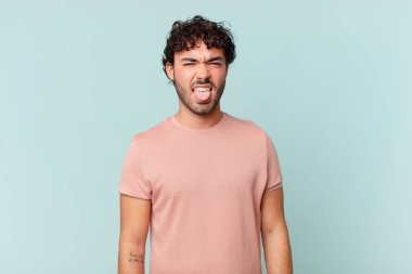 İspanyol yakışıklı adam tiksinmiş ve rahatsız olmuş hissediyor, dilini dışarı çıkarıyor, iğrenç ve iğrenç bir şeyden hoşlanmıyor.