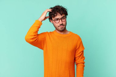 İspanyol yakışıklı adam şaşkın ve şaşkın hissediyor, başını kaşıyor ve yana bakıyor.