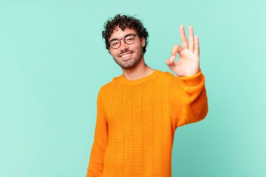 İspanyol yakışıklı adam kendini mutlu, rahat ve tatmin olmuş hissediyor. Onayını iyi bir hareketle gösteriyor. Gülümsüyor.