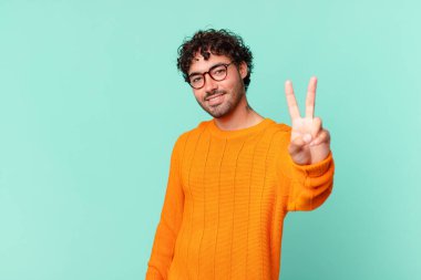 İspanyol yakışıklı adam gülümsüyor ve mutlu görünüyor, kaygısız ve olumlu, zafer ya da barışı simgeliyor.