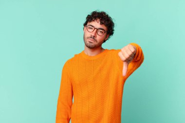 İspanyol yakışıklı adam sinirli, sinirli, sinirli, hayal kırıklığına uğramış ya da hoşnutsuz, ciddi bir bakışla başparmağını kaldırıyor.