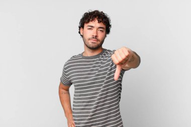 İspanyol yakışıklı adam sinirli, sinirli, sinirli, hayal kırıklığına uğramış ya da hoşnutsuz, ciddi bir bakışla başparmağını kaldırıyor.