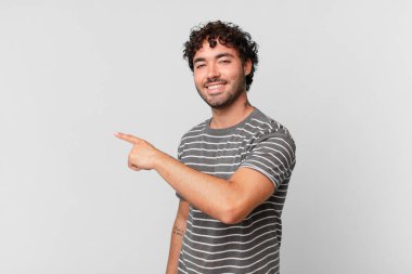 İspanyol yakışıklı adam heyecanlı ve şaşırmış görünüyor. Yana ve yukarı doğru uzayı gösteriyor.