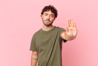 İspanyol yakışıklı adam ciddi, sert, hoşnutsuz ve kızgın görünüyor. Avuç içinin açık olması jesti durduruyor.