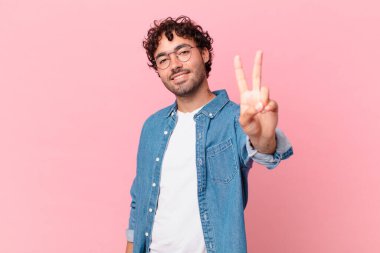 İspanyol yakışıklı adam gülümsüyor ve mutlu görünüyor, kaygısız ve olumlu, zafer ya da barışı simgeliyor.