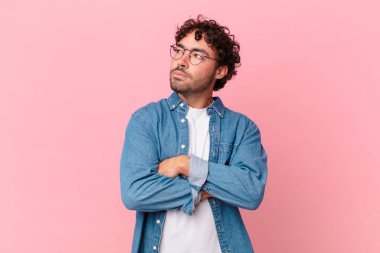 İspanyol yakışıklı adam omuz silkiyor, kafası karışık ve emin değil, kolları bağlı ve şaşkın görünüyor.