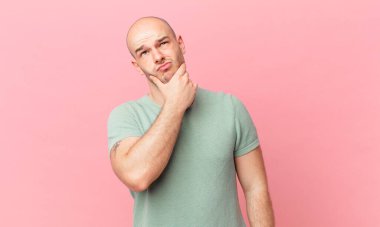 Kel düşünen, kuşkulu ve kafası karışık, farklı seçenekleri olan, hangi kararı vereceğini merak eden bir adam.