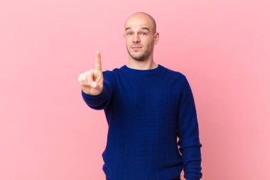 Kel adam gururla gülümsüyor ve gururla bir numaralı pozunu veriyor, kendini lider gibi hissediyor.