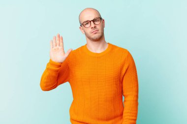 Kel adam ciddi, sert, hoşnutsuz ve kızgın görünüyor. Avuç içini açıp jesti durduruyor.