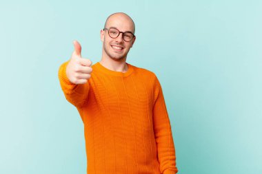 Kel adam gururlu, kaygısız, kendinden emin ve mutlu, olumlu gülümsüyor.