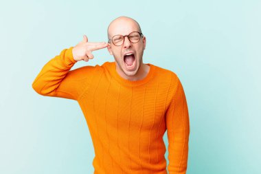 Kel adam mutsuz ve stresli görünüyor, intihar jesti elle silah işareti yapıyor, kafasını işaret ediyor.