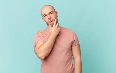 Kel düşünen, kuşkulu ve kafası karışık, farklı seçenekleri olan, hangi kararı vereceğini merak eden bir adam.