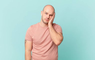 Kel bir adam yorgun, sıkıcı ve can sıkıcı bir işten sonra sıkılmış, hayal kırıklığına uğramış ve uykulu hisseder.