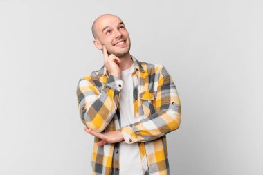 Kel adam mutlu bir şekilde gülümsüyor ve hayal kuruyor ya da şüphe ediyor.