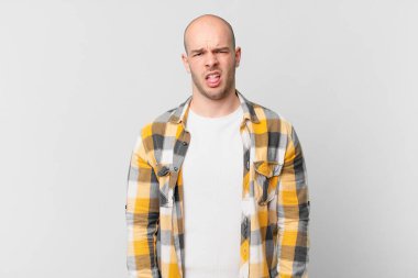 Kel adam tiksinti ve tedirginlik duyuyor, dilini dışarı çıkarıyor, iğrenç ve iğrenç bir şeyden hoşlanmıyor.