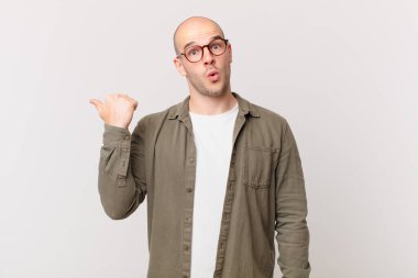 Kel adam inançsızlıktan şaşkın şaşkın bakıyor, yan taraftaki objeyi işaret ediyor ve diyor ki: