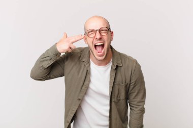 Kel adam mutsuz ve stresli görünüyor, intihar jesti elle silah işareti yapıyor, kafasını işaret ediyor.