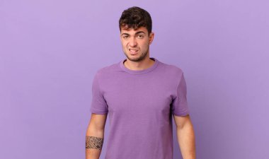 handsome man feeling puzzled and confused, with a dumb, stunned expression looking at something unexpected