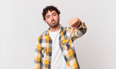 İspanyol yakışıklı adam sinirli, sinirli, sinirli, hayal kırıklığına uğramış ya da hoşnutsuz, ciddi bir bakışla başparmağını kaldırıyor.