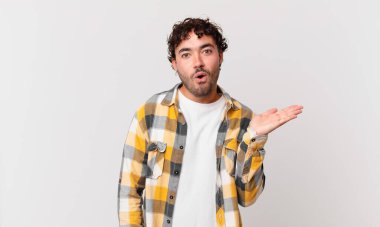 İspanyol yakışıklı adam şaşırmış ve şoka uğramış görünüyor, çenesi düşmüş, bir objeyi elinde açık bir elle tutuyor.