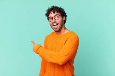 İspanyol yakışıklı adam heyecanlı ve şaşırmış görünüyor. Yana ve yukarı doğru uzayı gösteriyor.