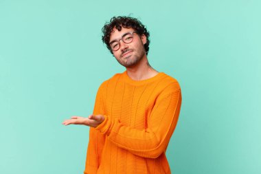 İspanyol yakışıklı adam neşeyle gülümsüyor, kendini mutlu hissediyor ve fotokopi uzayda avucunun içinde bir konsept gösteriyor.