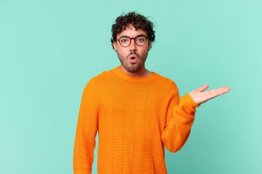 İspanyol yakışıklı adam şaşırmış ve şoka uğramış görünüyor, çenesi düşmüş, bir objeyi elinde açık bir elle tutuyor.