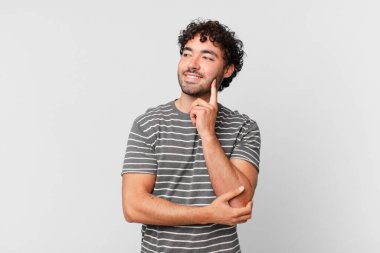 İspanyol yakışıklı adam mutlu bir şekilde gülümsüyor ve hayal kuruyor ya da şüphe ediyor, yana bakıyor.