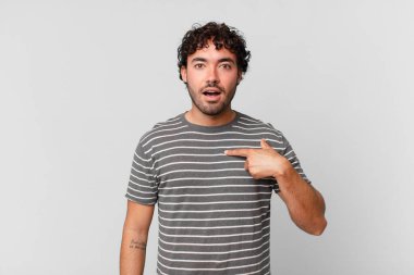 Şok olmuş ve ağzı açık, kendini işaret eden İspanyol yakışıklı bir adam.