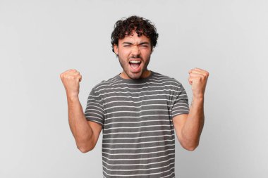 İspanyol yakışıklı bir adam sinirli bir ifadeyle agresif bir şekilde bağırıyor ya da yumruklarıyla başarıyı kutluyor.