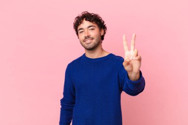 İspanyol yakışıklı adam gülümsüyor ve mutlu görünüyor, kaygısız ve olumlu, zafer ya da barışı simgeliyor.