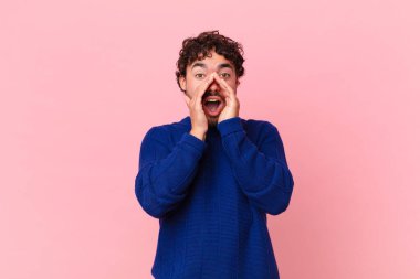 İspanyol yakışıklı adam mutlu, heyecanlı ve pozitif hissediyor. Elleri ağızda, bağırıyor.