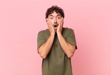İspanyol yakışıklı adam şok olmuş ve korkmuş hissediyor, ağzı açık ve elleri yanaklarında korkmuş görünüyor.