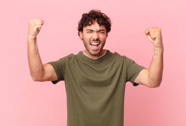 İspanyol yakışıklı bir adam sinirli bir ifadeyle agresif bir şekilde bağırıyor ya da yumruklarıyla başarıyı kutluyor.