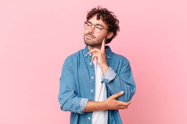 İspanyol yakışıklı adam mutlu bir şekilde gülümsüyor ve hayal kuruyor ya da şüphe ediyor, yana bakıyor.