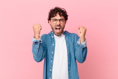 İspanyol yakışıklı bir adam sinirli bir ifadeyle agresif bir şekilde bağırıyor ya da yumruklarıyla başarıyı kutluyor.