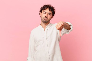 İspanyol yakışıklı adam sinirli, sinirli, sinirli, hayal kırıklığına uğramış ya da hoşnutsuz, ciddi bir bakışla başparmağını kaldırıyor.