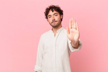 İspanyol yakışıklı adam ciddi, sert, hoşnutsuz ve kızgın görünüyor. Avuç içinin açık olması jesti durduruyor.