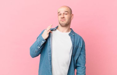 Kel adam kibirli, başarılı, pozitif ve gururlu görünüyor, kendini işaret ediyor.