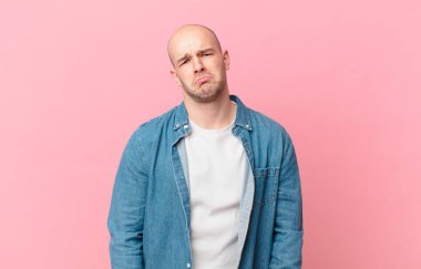 Kel bir adam üzgün ve mızmızlanıyor. Mutsuz bir bakışla, olumsuz ve hayal kırıklığına uğramış bir tavırla ağlıyor.