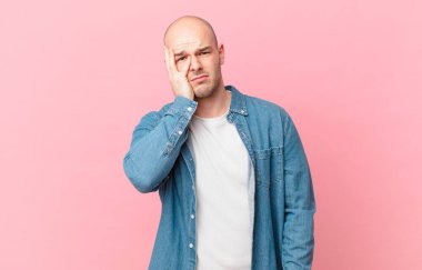 Kel bir adam yorgun, sıkıcı ve can sıkıcı bir işten sonra sıkılmış, hayal kırıklığına uğramış ve uykulu hisseder.